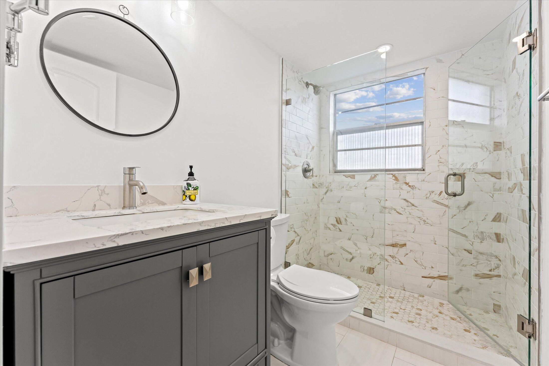 308 Preston H, Unit 308 Boca Raton, FL 33434 - Photo 15 of 22 a bathroom with a sink a toilet and a mirror