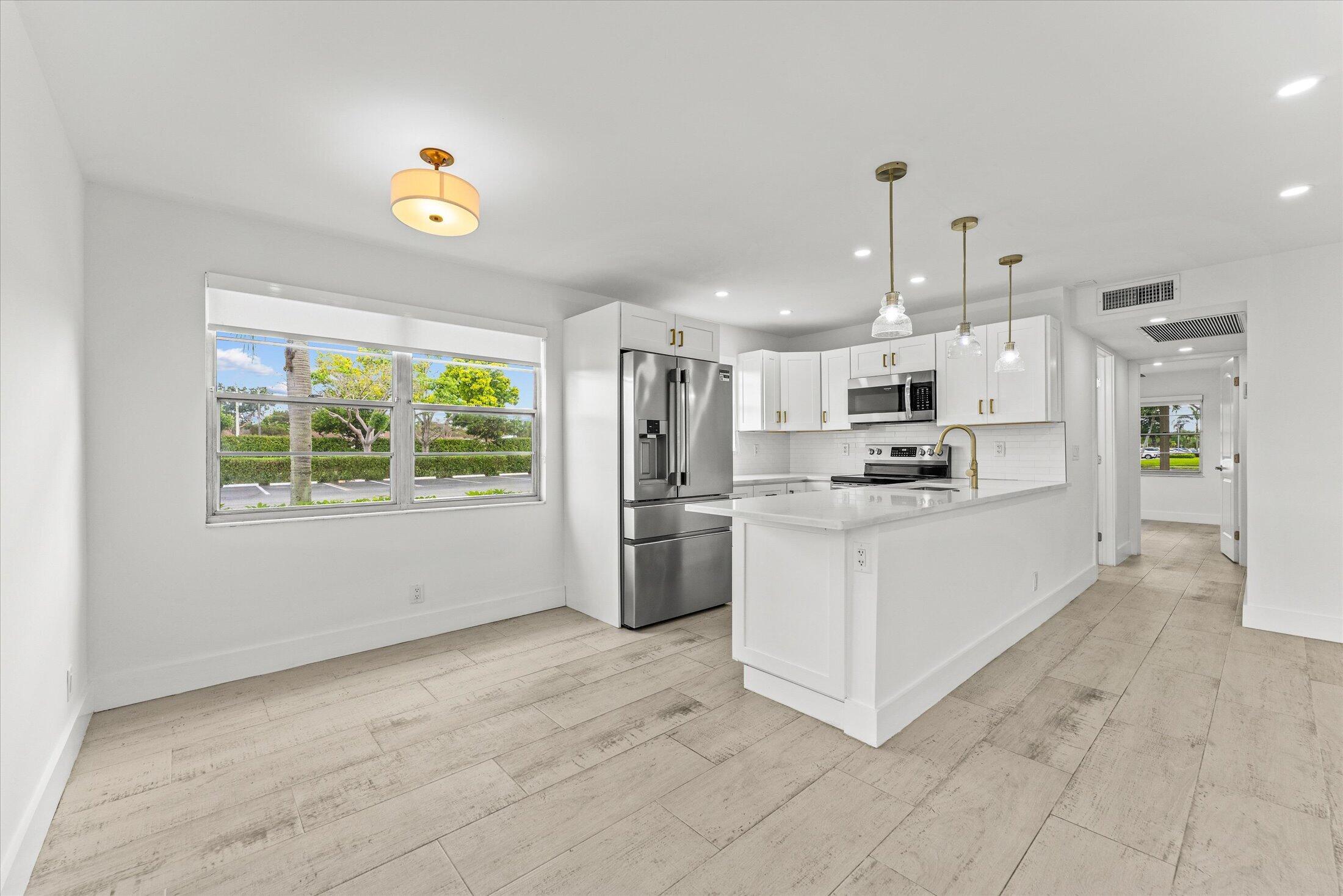 308 Preston H, Unit 308 Boca Raton, FL 33434 - Photo 4 of 22 a kitchen with stainless steel appliances kitchen island granite countertop a refrigerator oven a sink dishwasher and white cabinets with wooden floor
