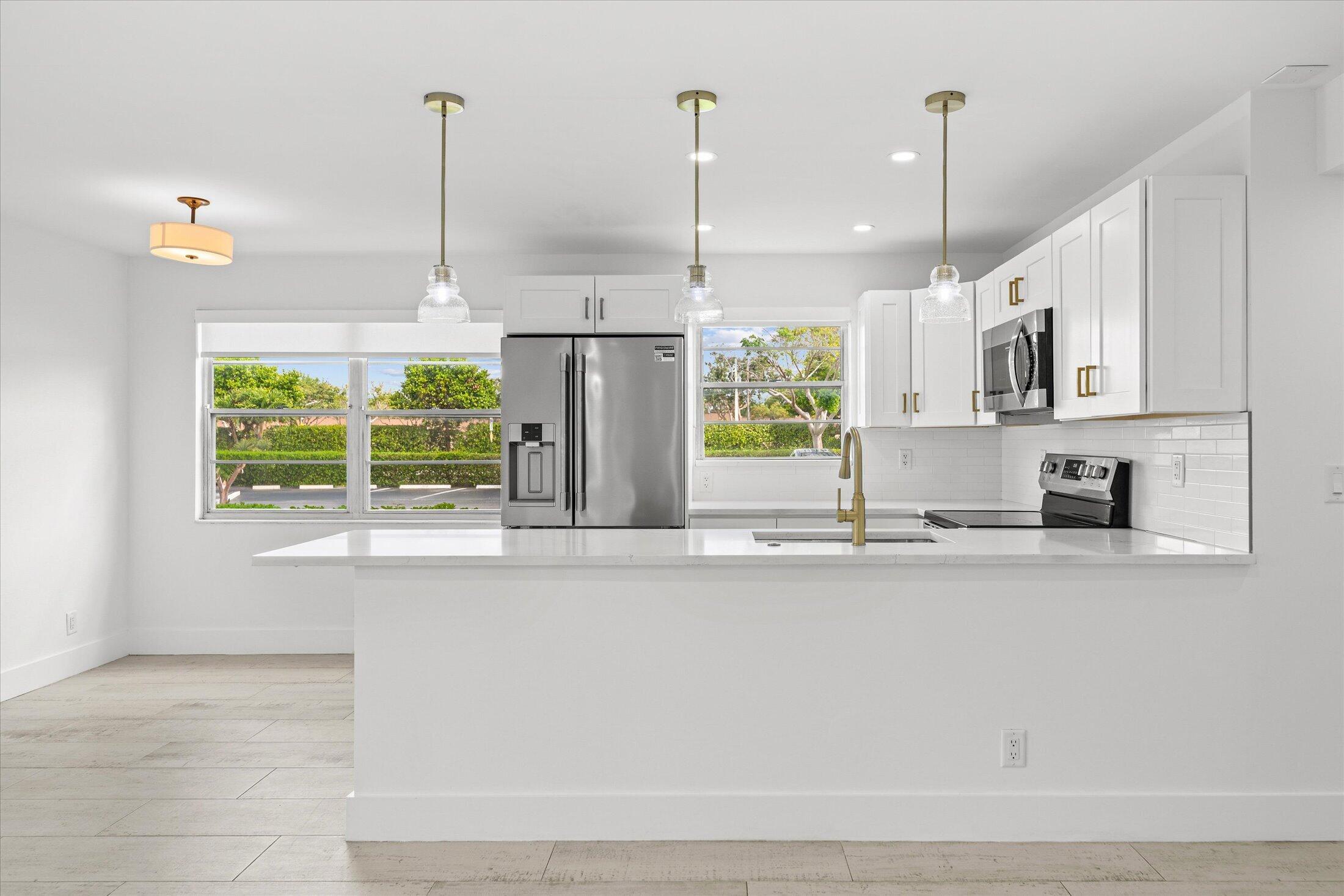 308 Preston H, Unit 308 Boca Raton, FL 33434 - Photo 9 of 22 a kitchen with stainless steel appliances granite countertop a sink a window and cabinets