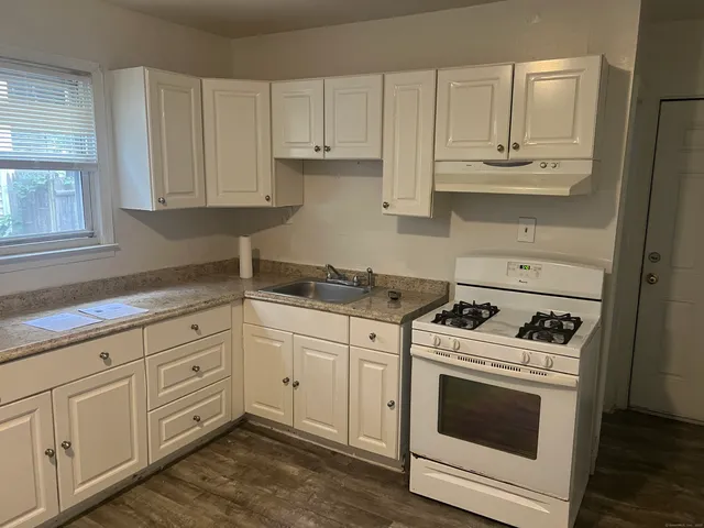 a kitchen with granite countertop white cabinets and white stainless steel appliances