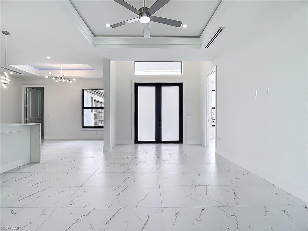 2707 36th Avenue Southeast Naples, FL 34117 - Photo 11 of 50 Foyer entrance featuring a tray ceiling, plenty of natural light, a chandelier, light marble finish flooring, and ornamental molding