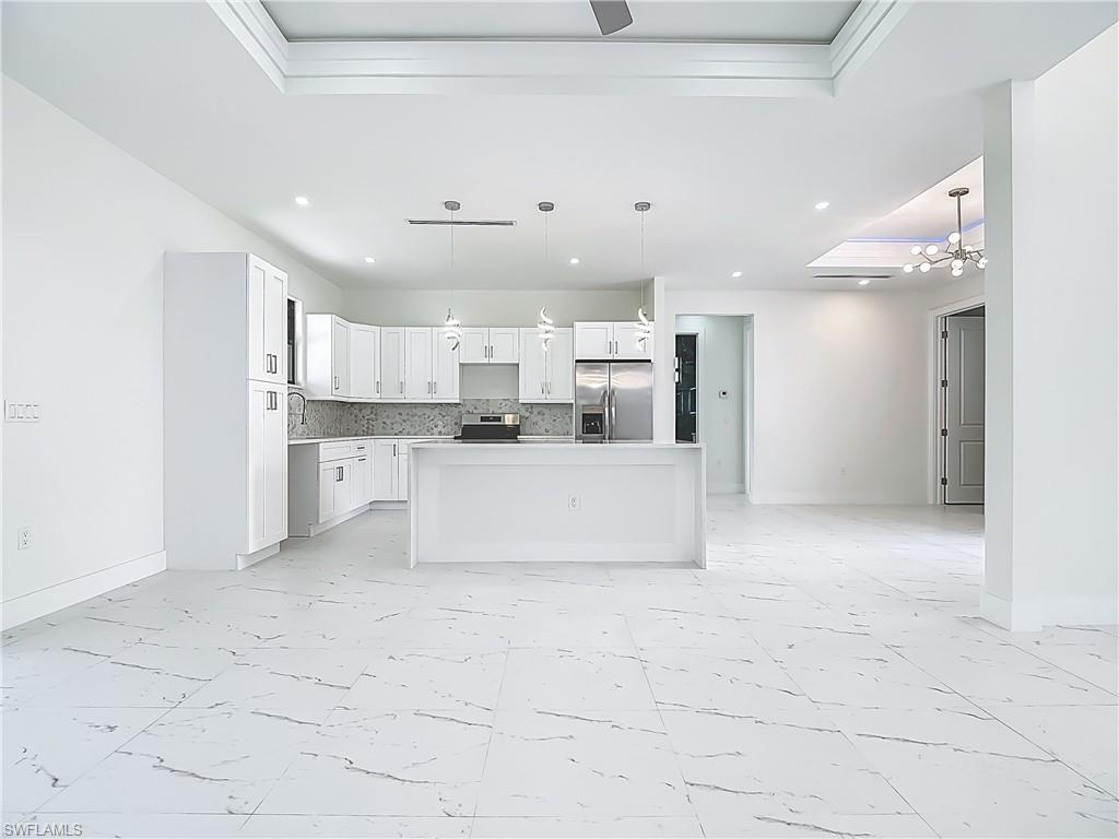 2707 36th Avenue Southeast Naples, FL 34117 - Photo 49 of 50 Kitchen with light marble finish floors, a raised ceiling, appliances with stainless steel finishes, open floor plan, and recessed lighting