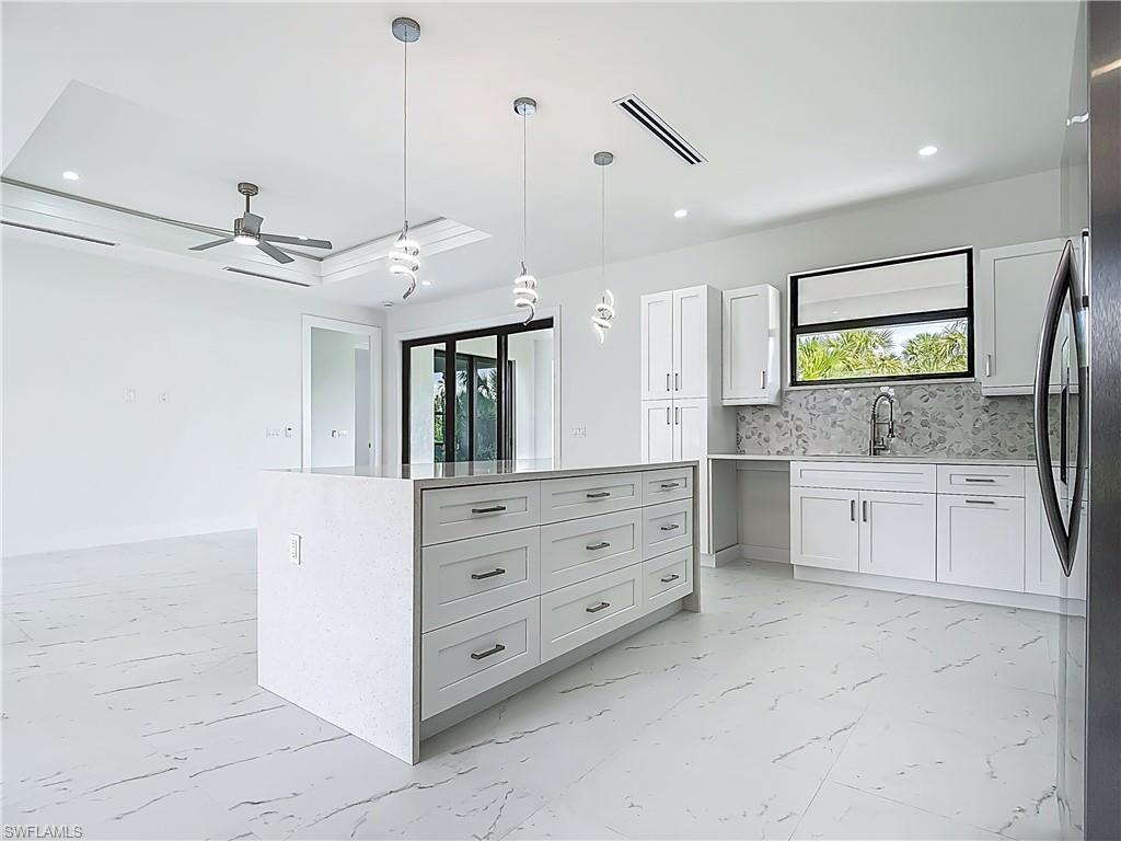 2707 36th Avenue Southeast Naples, FL 34117 - Photo 14 of 50 Kitchen featuring white cabinetry, a ceiling fan, hanging light fixtures, light marble finish floors, and recessed lighting