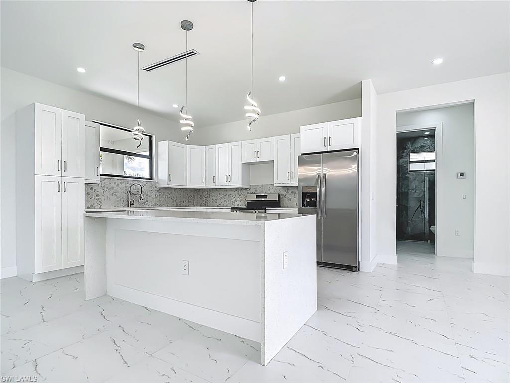 2707 36th Avenue Southeast Naples, FL 34117 - Photo 15 of 50 Kitchen with appliances with stainless steel finishes, light marble finish floors, a center island, white cabinets, and recessed lighting