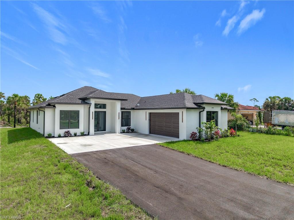 2707 36th Avenue Southeast Naples, FL 34117 - Photo 2 of 50 Prairie-style home with stucco siding, a garage, concrete driveway, and a front lawn