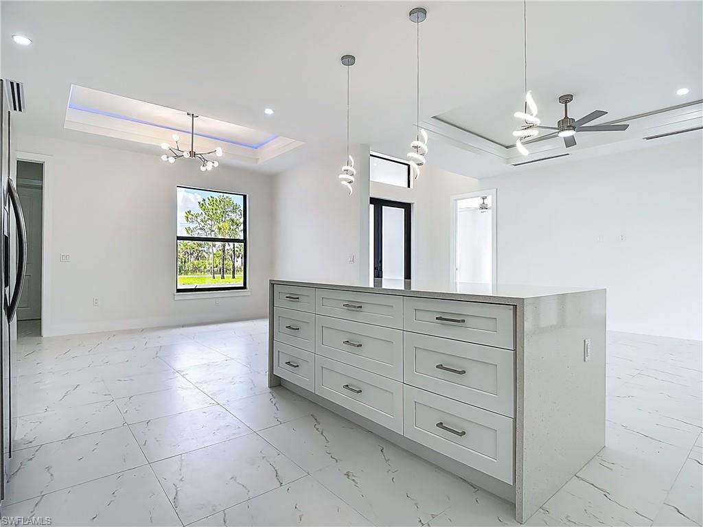 2707 36th Avenue Southeast Naples, FL 34117 - Photo 50 of 50 Kitchen with a raised ceiling, light marble finish flooring, a chandelier, open floor plan, and a center island