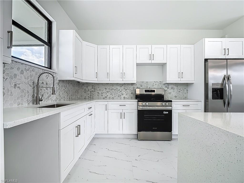 2707 36th Avenue Southeast Naples, FL 34117 - Photo 20 of 50 Kitchen featuring stainless steel appliances, light marble finish flooring, and white cabinets