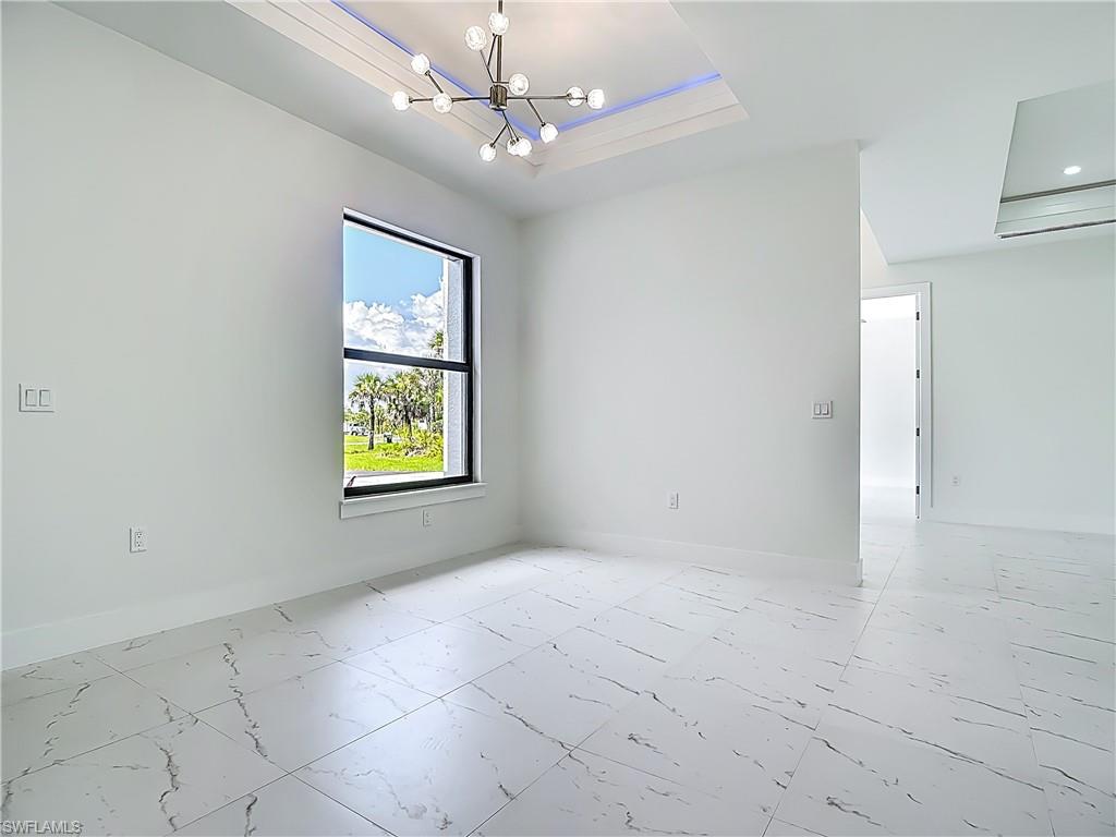 2707 36th Avenue Southeast Naples, FL 34117 - Photo 21 of 50 Unfurnished room with light marble finish flooring, a raised ceiling, and a chandelier