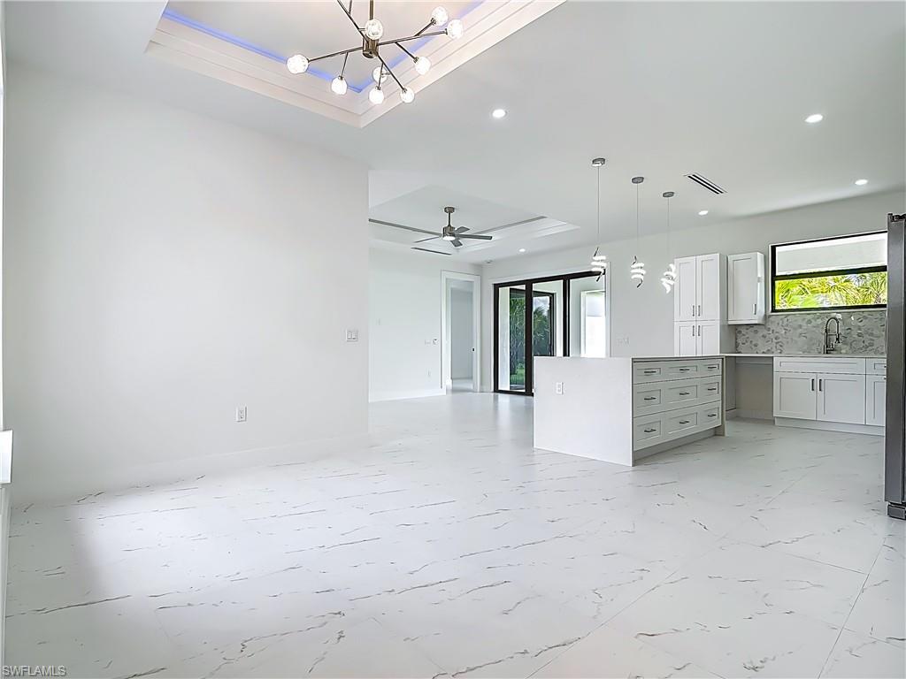 2707 36th Avenue Southeast Naples, FL 34117 - Photo 22 of 50 Unfurnished living room featuring a raised ceiling, plenty of natural light, recessed lighting, and a chandelier