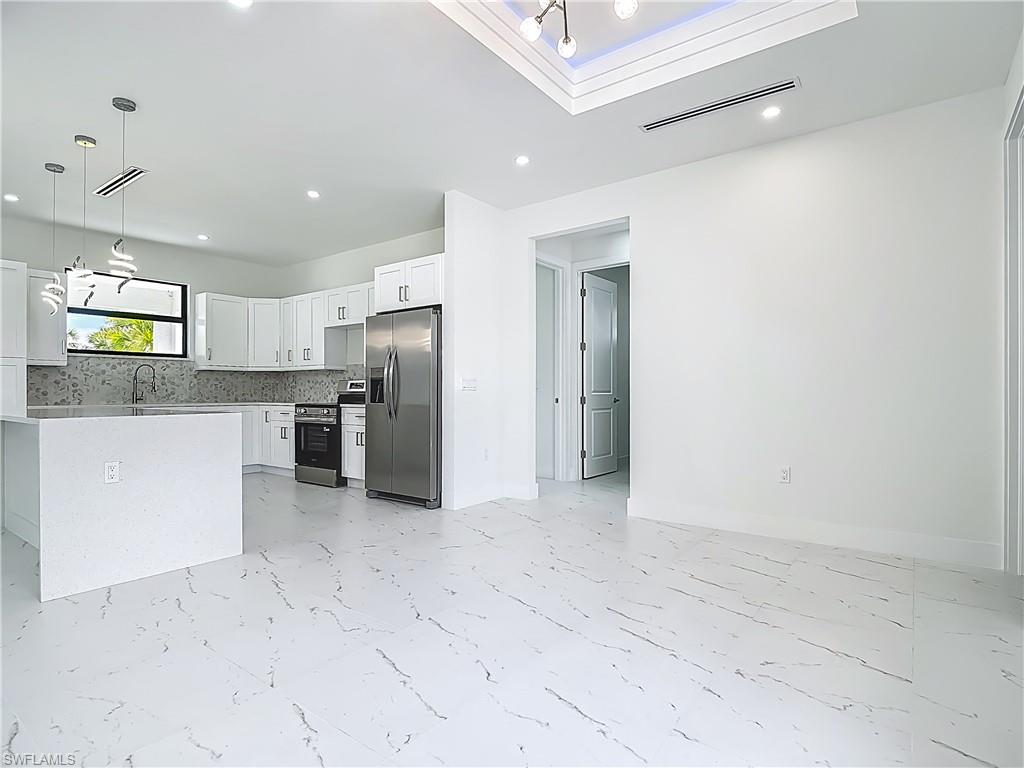 2707 36th Avenue Southeast Naples, FL 34117 - Photo 23 of 50 Kitchen with stainless steel appliances, light marble finish floors, white cabinets, tasteful backsplash, and recessed lighting
