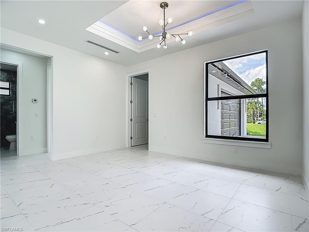 2707 36th Avenue Southeast Naples, FL 34117 - Photo 24 of 50 Spare room with light marble finish flooring, a raised ceiling, a chandelier, and recessed lighting