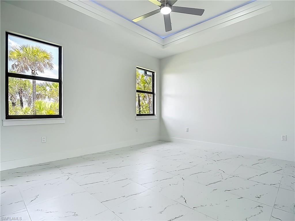2707 36th Avenue Southeast Naples, FL 34117 - Photo 28 of 50 Empty room with marble finish flooring, ceiling fan, and a tray ceiling