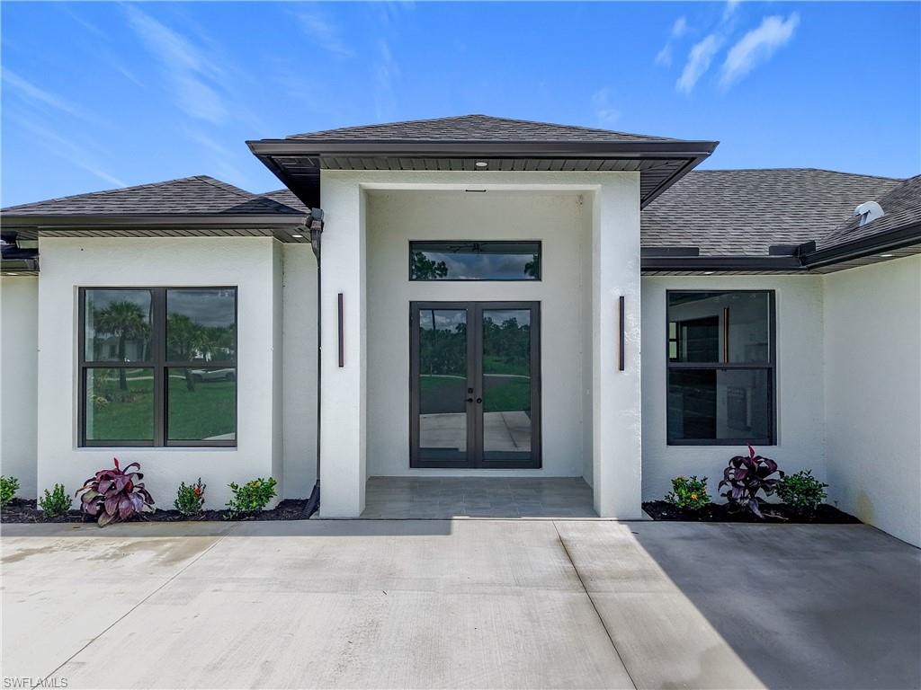 2707 36th Avenue Southeast Naples, FL 34117 - Photo 3 of 50 View of exterior entry with french doors, stucco siding, and roof with shingles