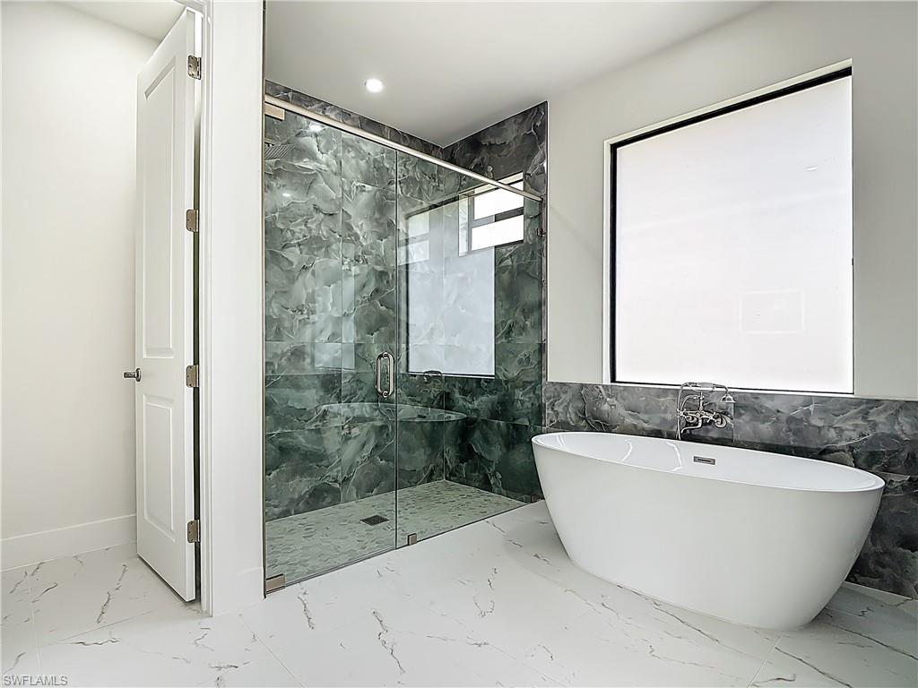 2707 36th Avenue Southeast Naples, FL 34117 - Photo 34 of 50 Bathroom with marble finish flooring, a freestanding bath, a marble finish shower, and recessed lighting