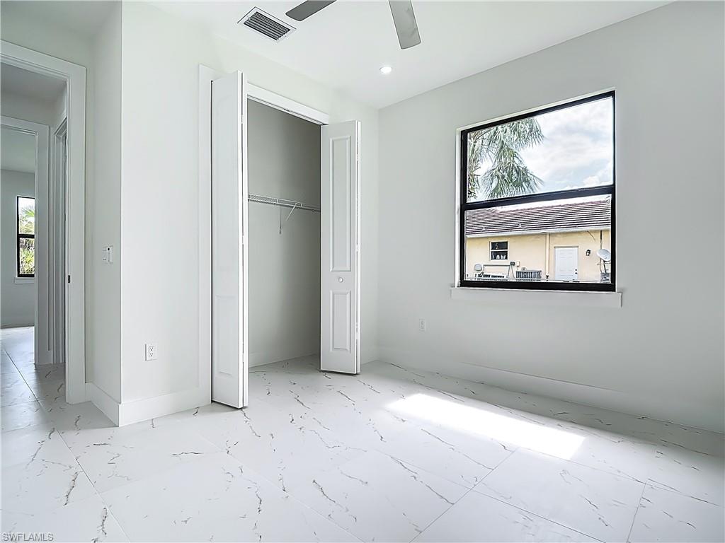 2707 36th Avenue Southeast Naples, FL 34117 - Photo 37 of 50 Unfurnished bedroom with multiple windows, marble finish floors, a closet, and ceiling fan