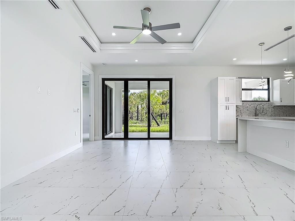 2707 36th Avenue Southeast Naples, FL 34117 - Photo 6 of 50 Unfurnished living room with a raised ceiling, a ceiling fan, light marble finish flooring, recessed lighting, and ornamental molding
