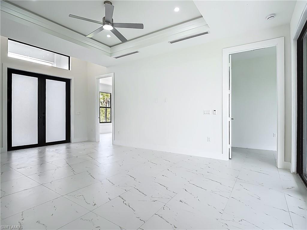 2707 36th Avenue Southeast Naples, FL 34117 - Photo 9 of 50 Unfurnished room featuring light marble finish flooring, ceiling fan, a raised ceiling, and recessed lighting