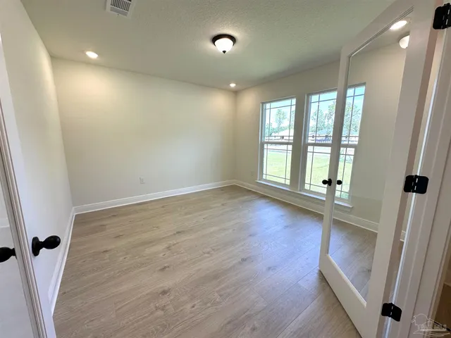 an empty room with wooden floor and windows