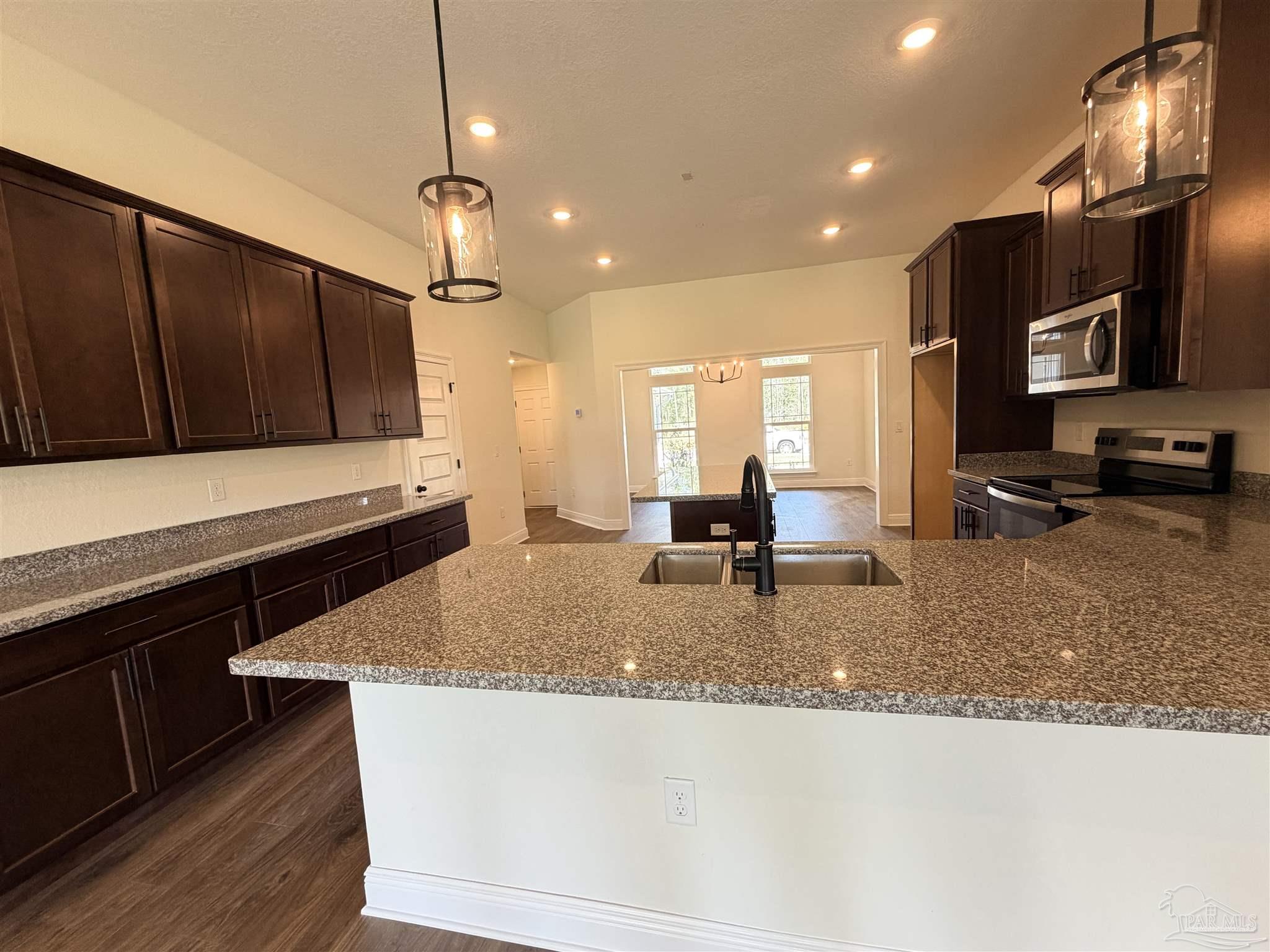 5263 Wahoo Road Milton, FL 32583 - Photo 10 of 25 a kitchen with kitchen island granite countertop a sink a counter top space appliances and cabinets
