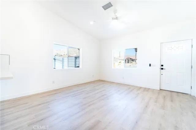 an empty room with wooden floor and windows