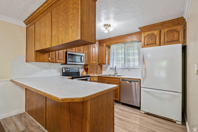 553 North 200 West Bountiful, UT 84010 - Photo 7 of 26 Kitchen featuring wood finish cabinetry, stainless steel appliances, a textured ceiling, light countertops, and a peninsula