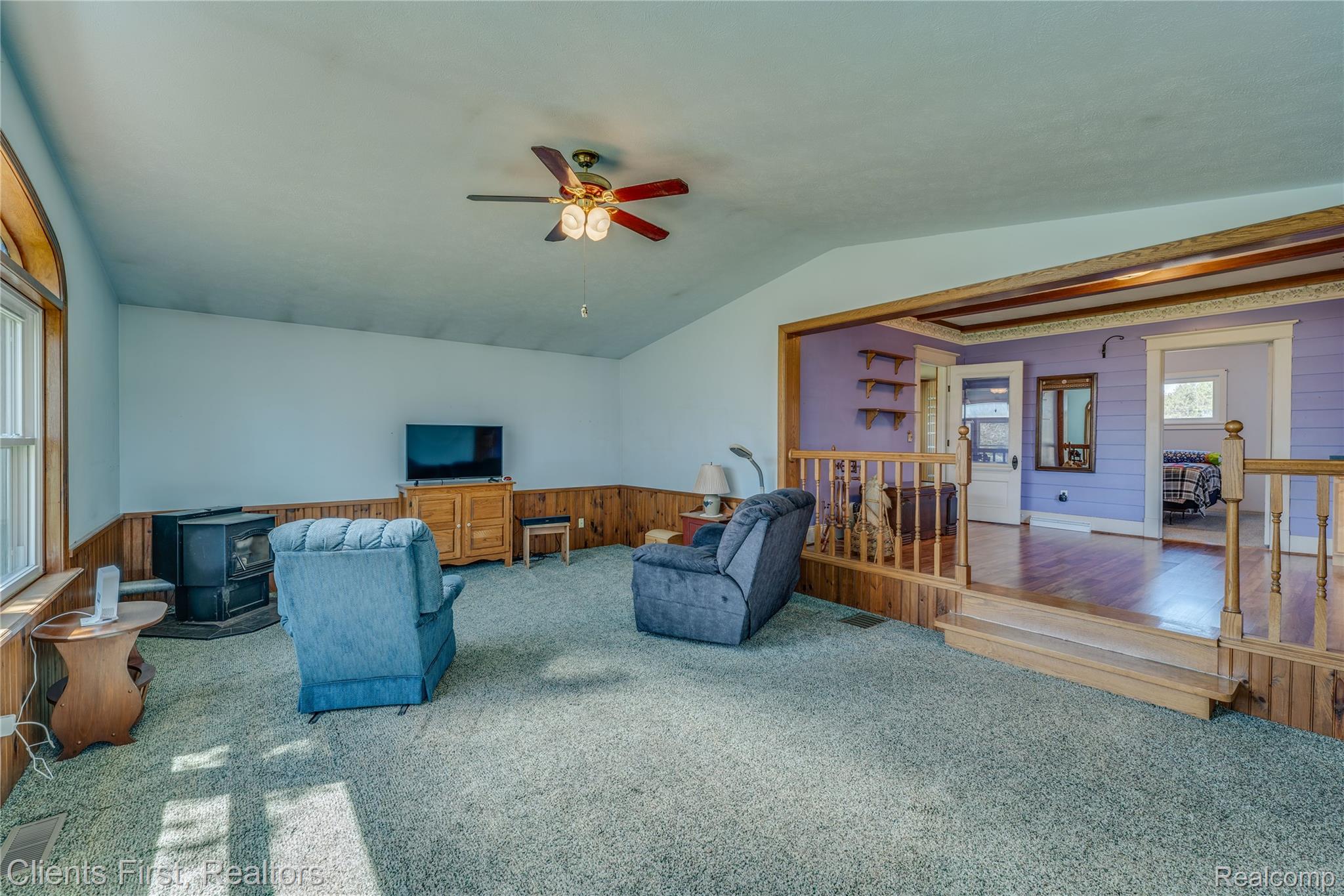 342 North Chambers Road Tawas City, MI 48763 - Photo 8 of 30 Living area featuring carpet flooring, wood walls, a ceiling fan, a wood stove, and vaulted ceiling