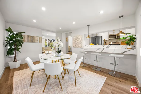 a dining room with furniture a potted plant and kitchen view