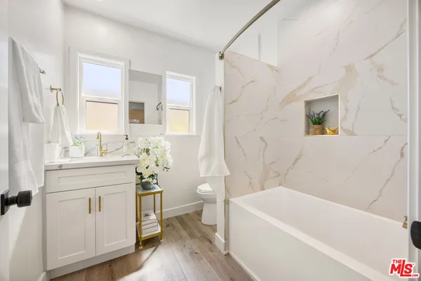 a bathroom with a bathtub a sink a window and a mirror