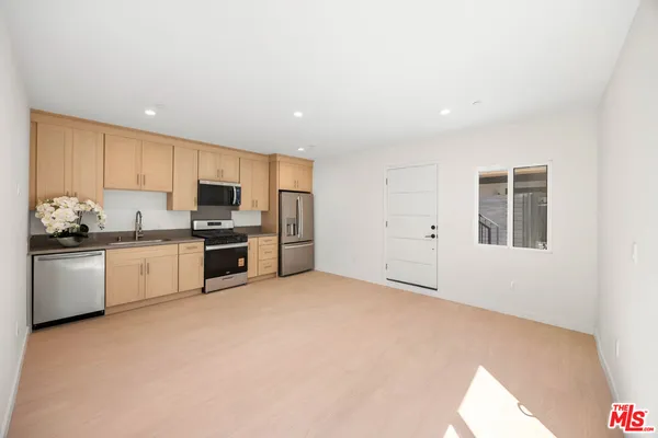 a kitchen with stainless steel appliances a refrigerator and white cabinets