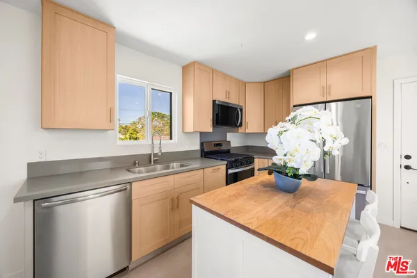 a kitchen with stainless steel appliances granite countertop a sink a stove and a refrigerator