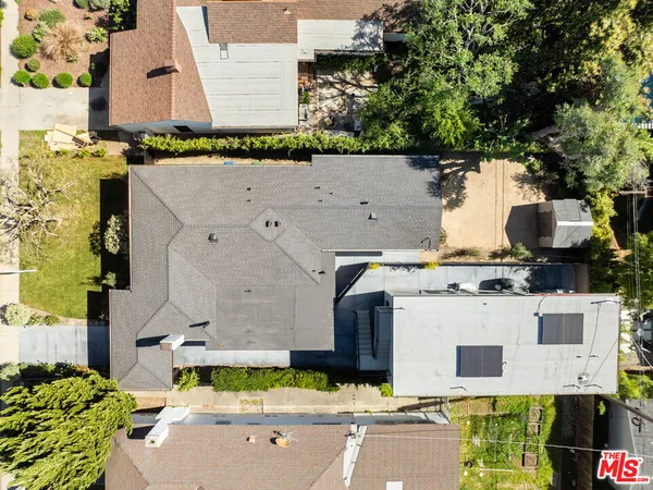 an aerial view of a house with swimming pool and large trees