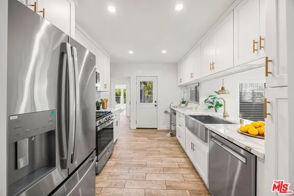a large kitchen with stainless steel appliances granite countertop a refrigerator and a stove