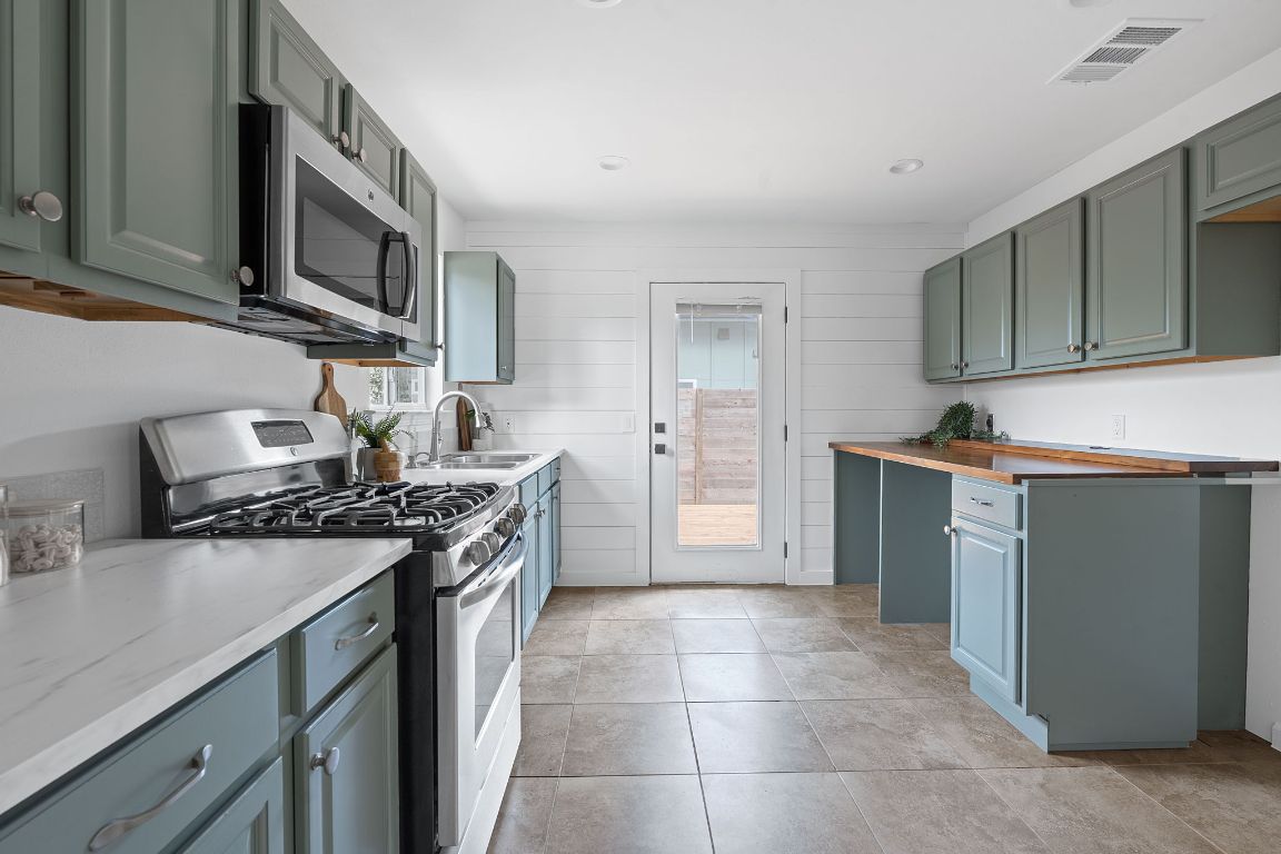 3404 Thomas Kincheon Street, Unit 1 & 3 Austin, TX 78745 - Photo 10 of 30 a kitchen with stainless steel appliances granite countertop a stove top oven a sink dishwasher and a refrigerator with wooden cabinets