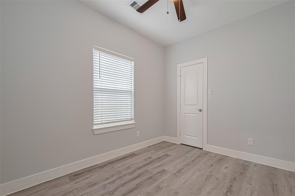 7926 Easter Street Houston, TX 77088 - Photo 14 of 24 an empty room with wooden floor cabinet and windows