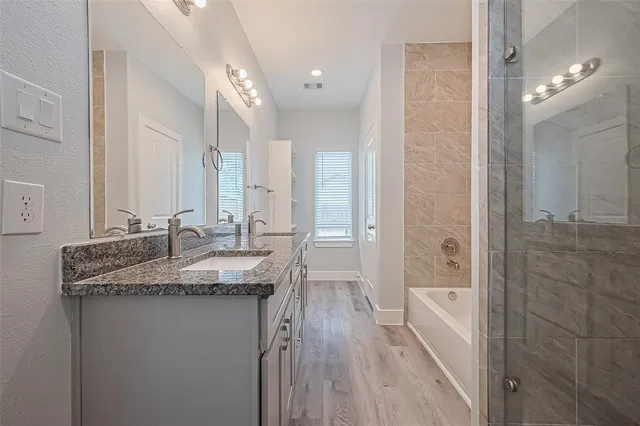 a bathroom with a granite countertop sink a mirror and a bathtub