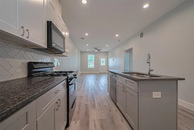a kitchen with granite countertop a sink stove and cabinets
