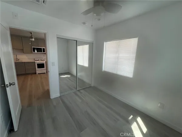 an empty room with wooden floor cabinet and windows