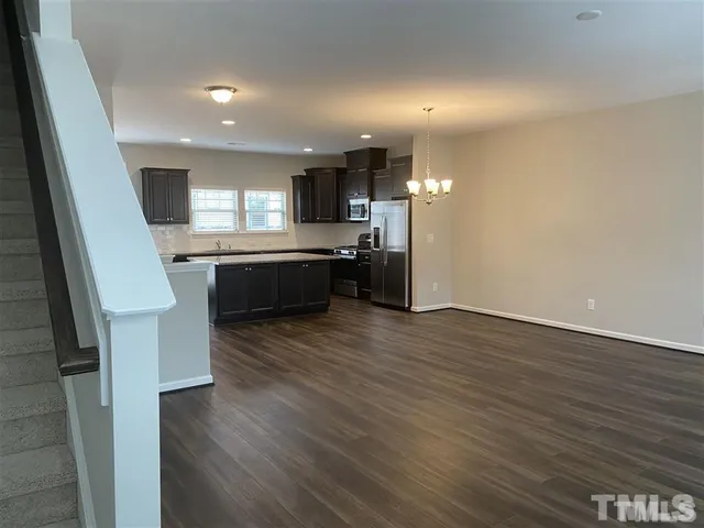 a kitchen with stainless steel appliances granite countertop a refrigerator a sink dishwasher a stove and white countertops with wooden floor