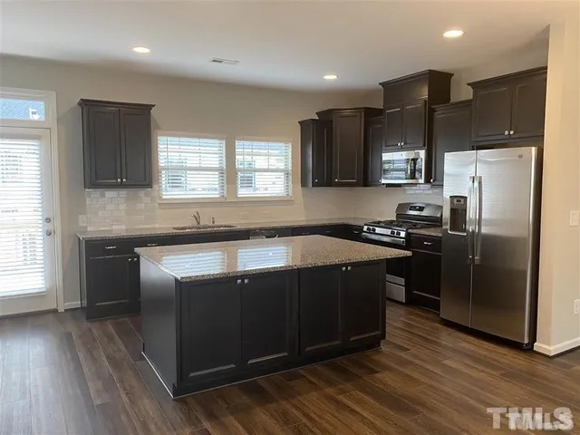 a kitchen with kitchen island granite countertop a sink appliances and cabinets