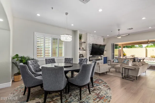 a kitchen with stainless steel appliances granite countertop a dining table chairs sink and white cabinets