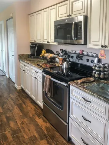 a view of a house with a yard and large tree