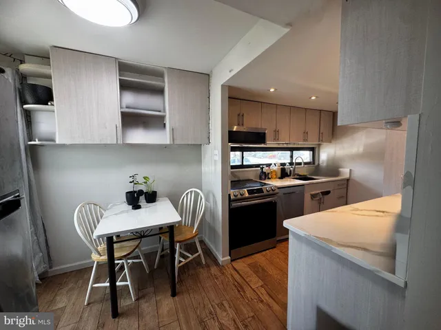 a kitchen with stainless steel appliances granite countertop a table chairs stove and refrigerator