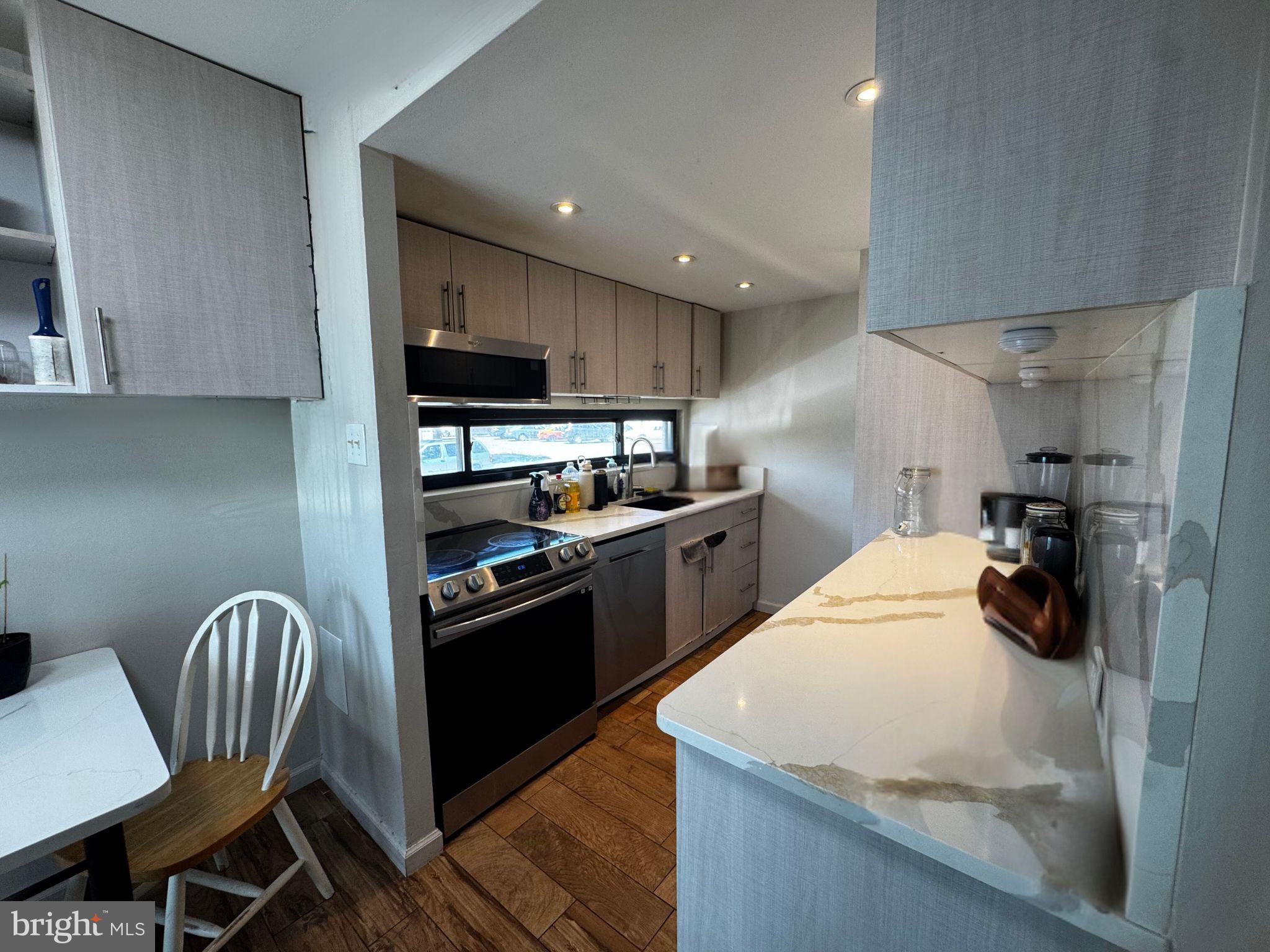 3850 Woodhaven Road, Unit 907 Philadelphia, PA 19154 - Photo 5 of 11 a kitchen with a sink a stove and chairs
