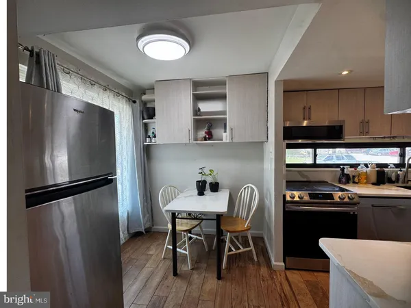 a kitchen with stainless steel appliances a refrigerator a sink a stove a table and chairs