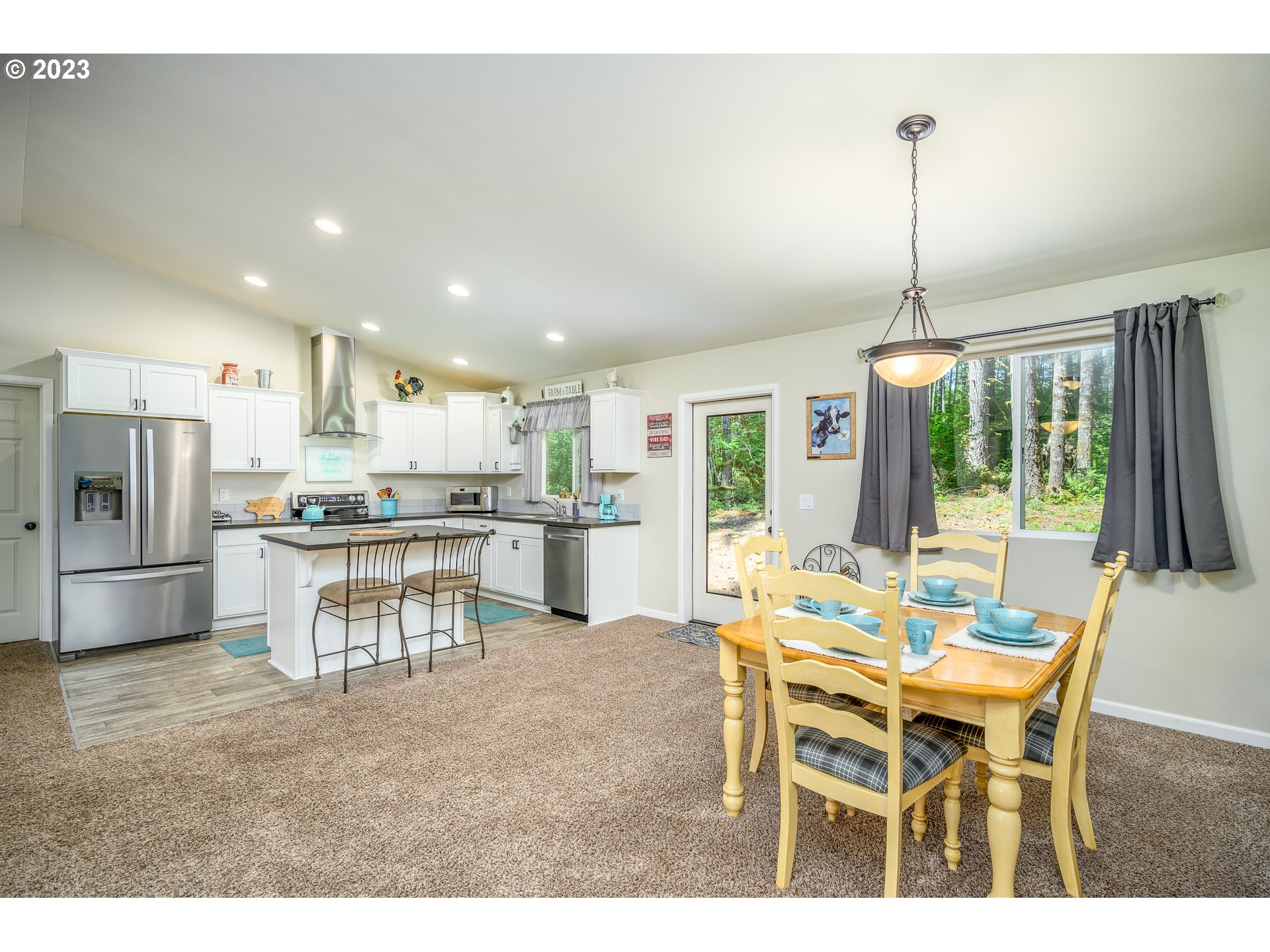 7297 Ash Street Grand Ronde, OR 97347 - Photo 9 of 33 a kitchen with kitchen island a dining table chairs and refrigerator