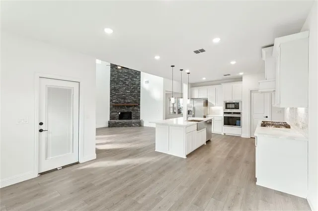a large white kitchen with a refrigerator a sink dishwasher and white cabinets with wooden floor
