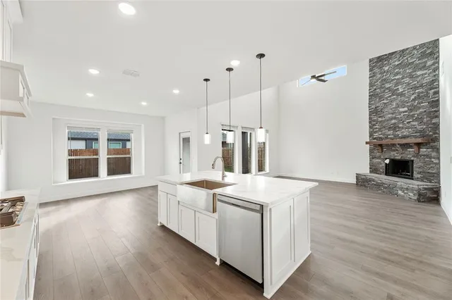 a large white kitchen with a stove a sink dishwasher and a fireplace with wooden floor