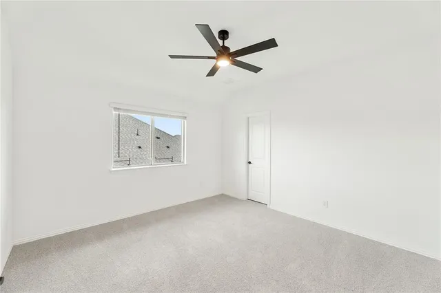 an empty room with ceiling fan and window