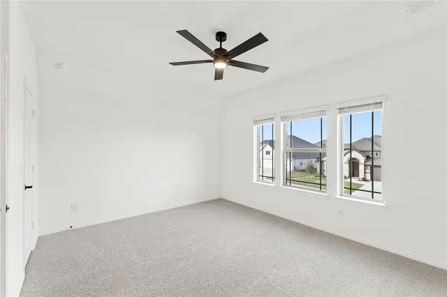 an empty room with window and ceiling fan