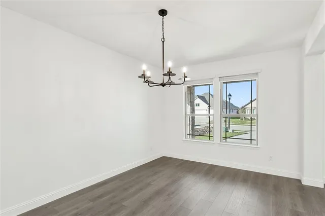a view of a room with wooden floor chandelier and windows